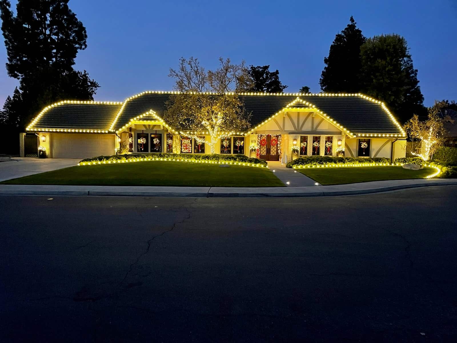 A Bakersfield home outlined in warm white Christmas lights at dusk