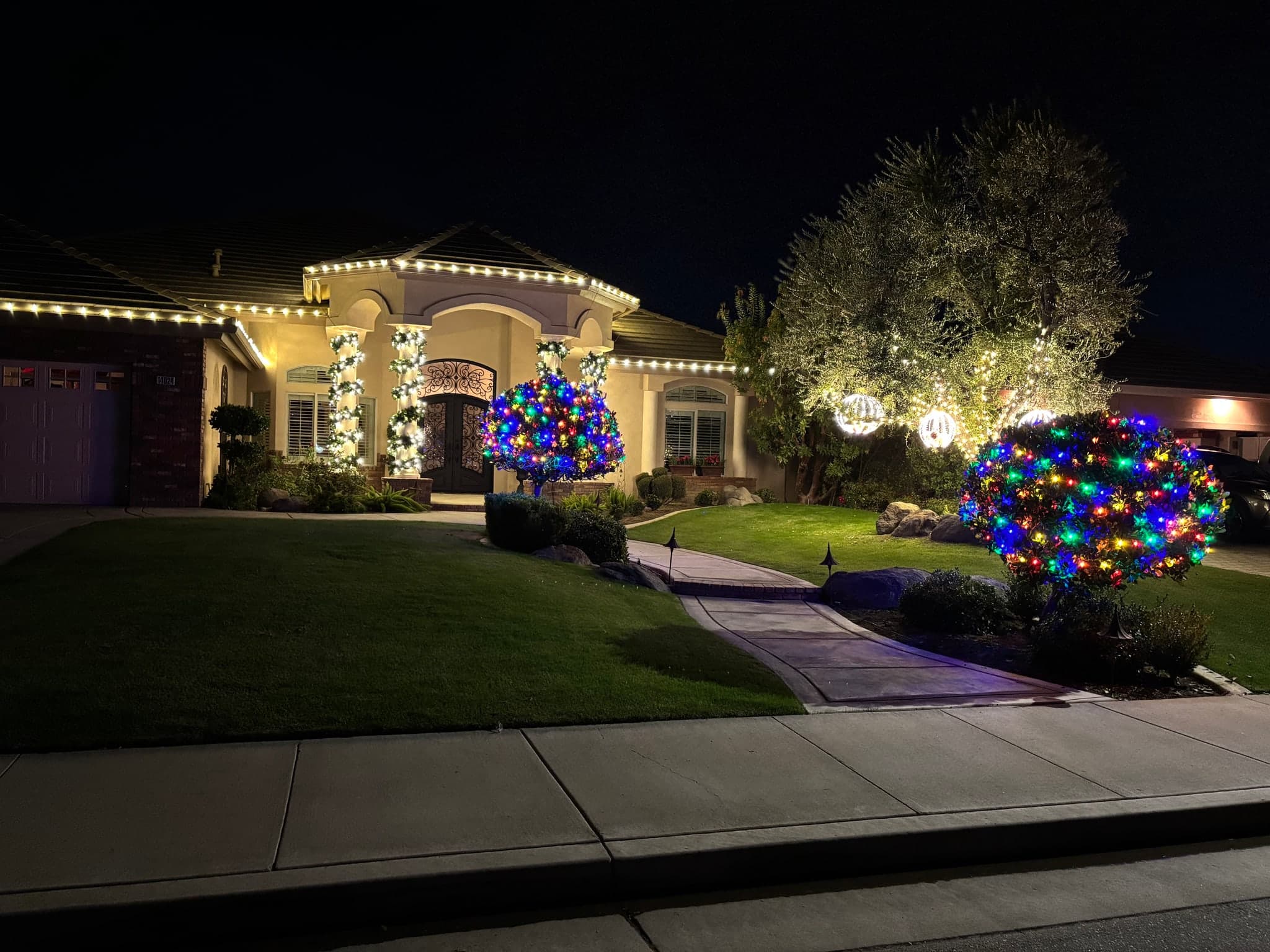 Multicolor Bushes with Glowing Globe Ornaments. Christmas light installation by Bright Idea Christmas Lights.